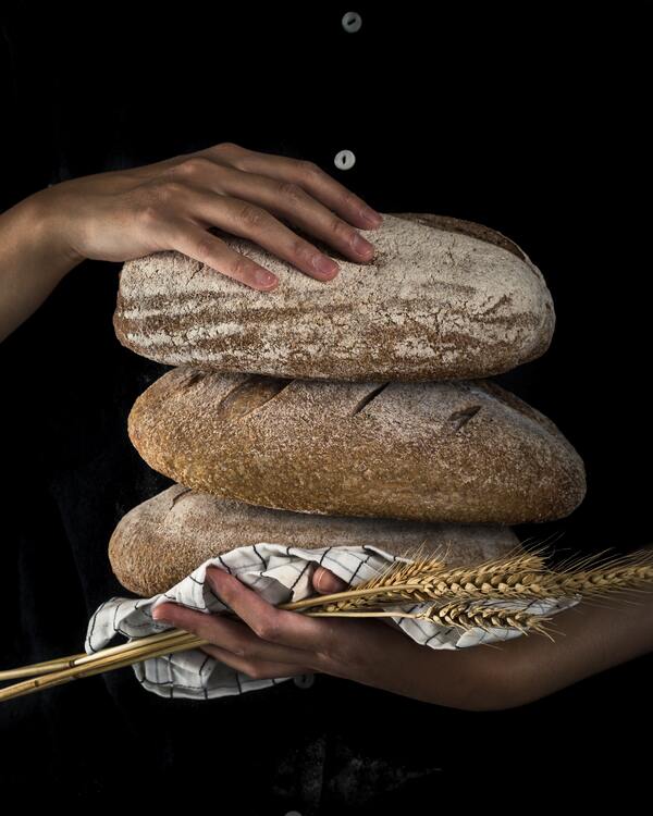 bochenki chleba w dłoniach piekarza