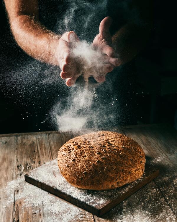 chleb na drewnianej desce obsypany mąką